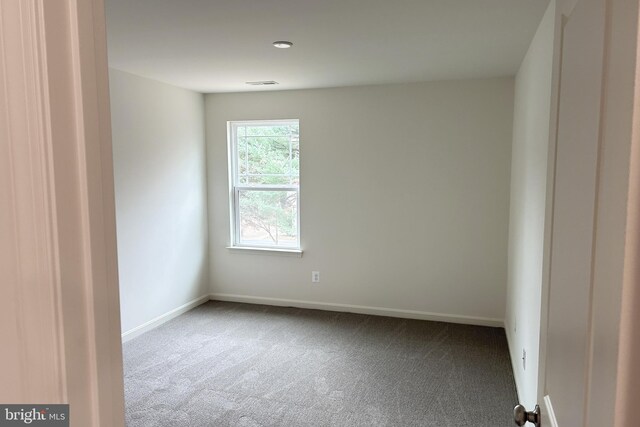 unfurnished room with carpet flooring, visible vents, and baseboards