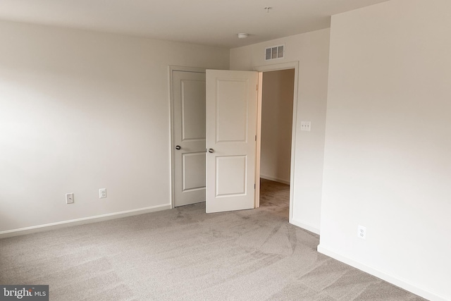 spare room with baseboards, visible vents, and light colored carpet