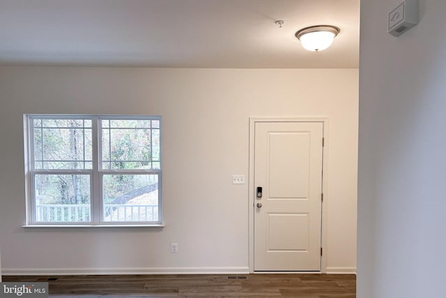 empty room featuring visible vents, baseboards, and dark wood-type flooring