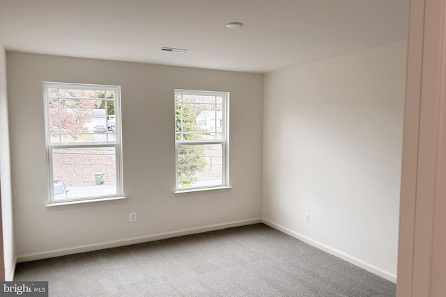 carpeted empty room featuring visible vents and baseboards