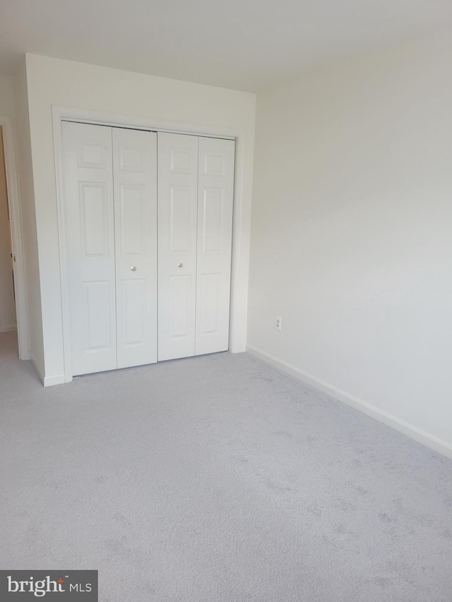 unfurnished bedroom with a closet and light colored carpet