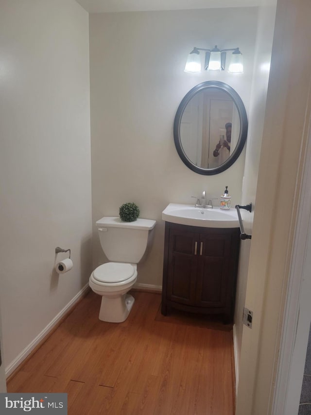 bathroom with toilet, hardwood / wood-style flooring, and vanity