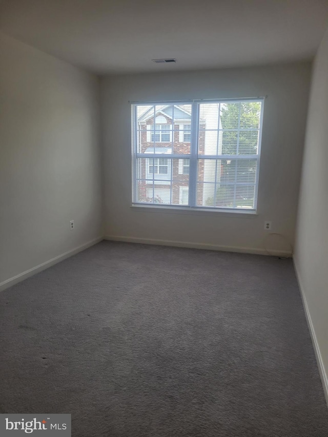 spare room with a wealth of natural light and dark carpet