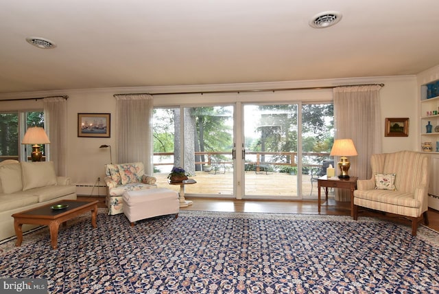 living area featuring ornamental molding, visible vents, a baseboard heating unit, and wood finished floors