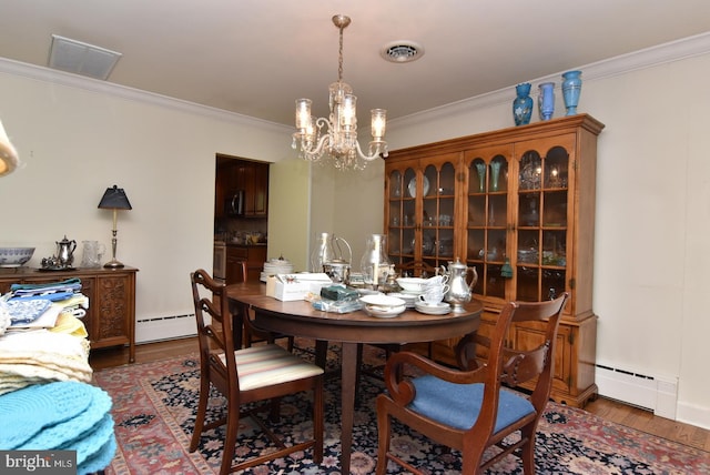 dining space with a baseboard heating unit, dark wood-type flooring, crown molding, and a notable chandelier