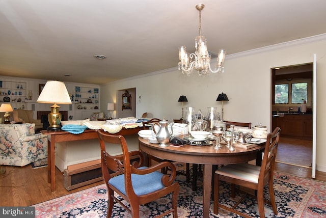 dining room with hardwood / wood-style floors, a chandelier, and crown molding