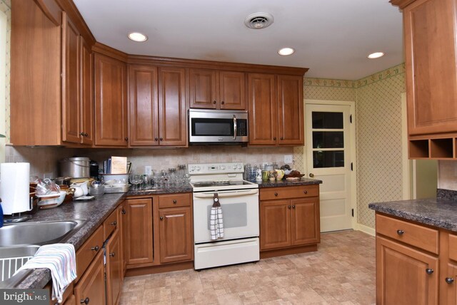 kitchen featuring stainless steel microwave, white electric stove, visible vents, and wallpapered walls