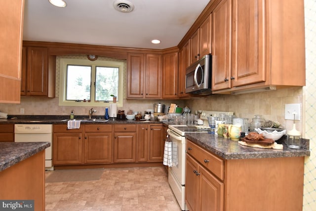 kitchen with dark stone countertops, sink, and white appliances