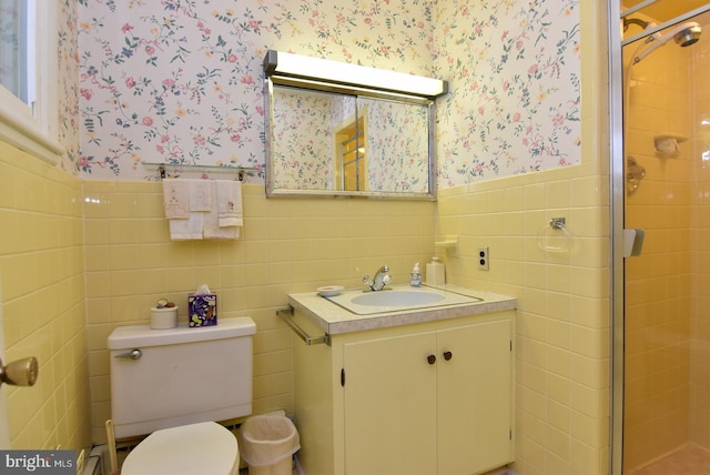 bathroom with tile walls, toilet, vanity, and an enclosed shower