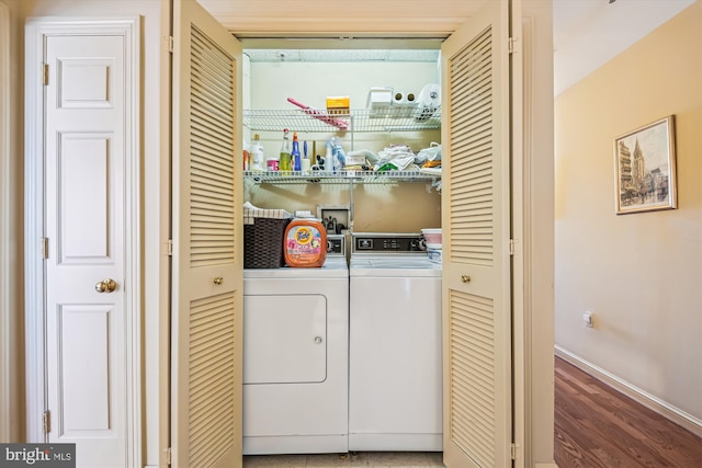 washroom featuring laundry area, baseboards, separate washer and dryer, and wood finished floors