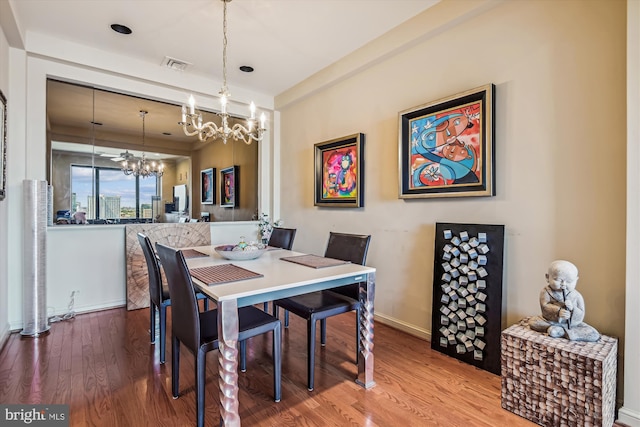 dining room featuring baseboards, visible vents, a chandelier, and wood finished floors