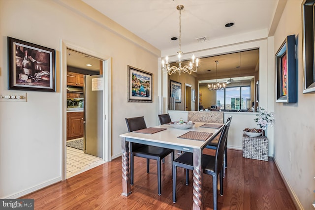 dining area with wood finished floors, visible vents, baseboards, and an inviting chandelier