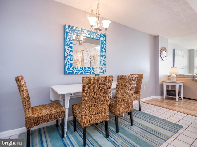 tiled dining room with a chandelier, a textured ceiling, and baseboards