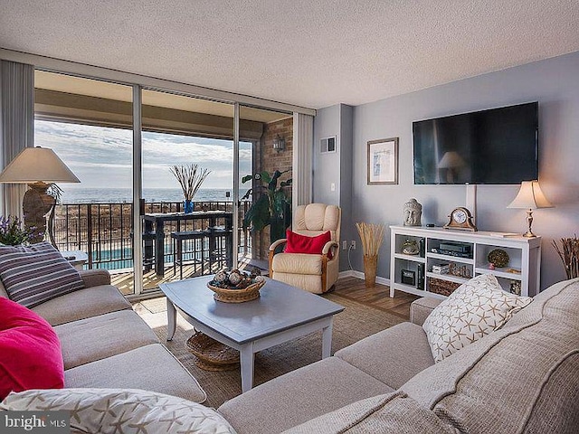 living area featuring visible vents, expansive windows, a textured ceiling, wood finished floors, and baseboards