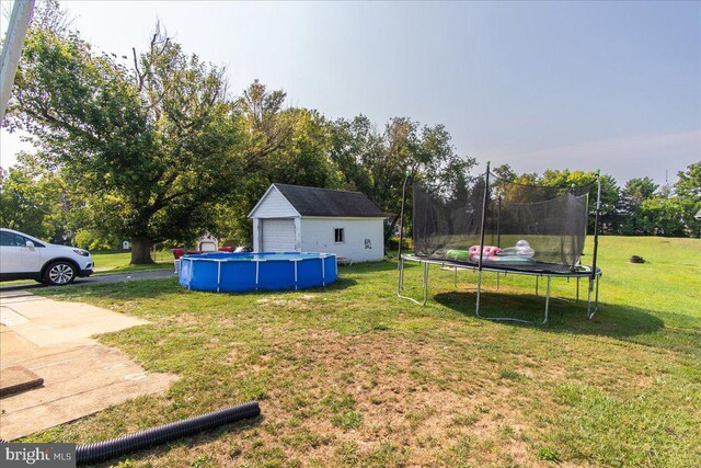 view of yard featuring a trampoline, an outbuilding, and a garage