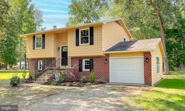 split foyer home featuring a garage and a front yard