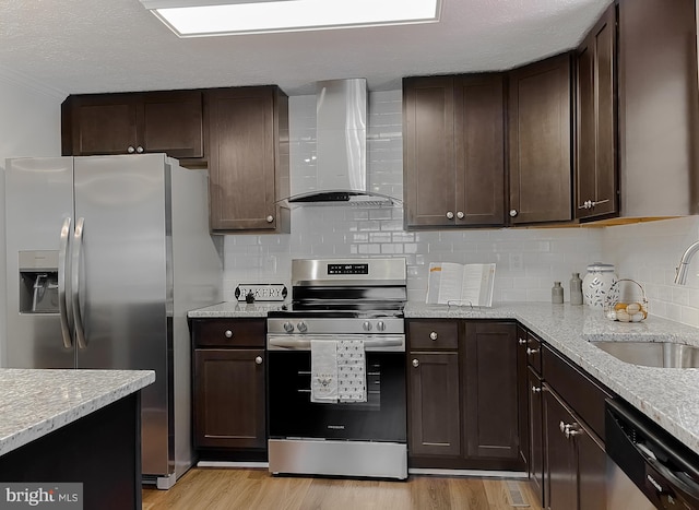 kitchen with light hardwood / wood-style flooring, sink, decorative backsplash, wall chimney exhaust hood, and appliances with stainless steel finishes