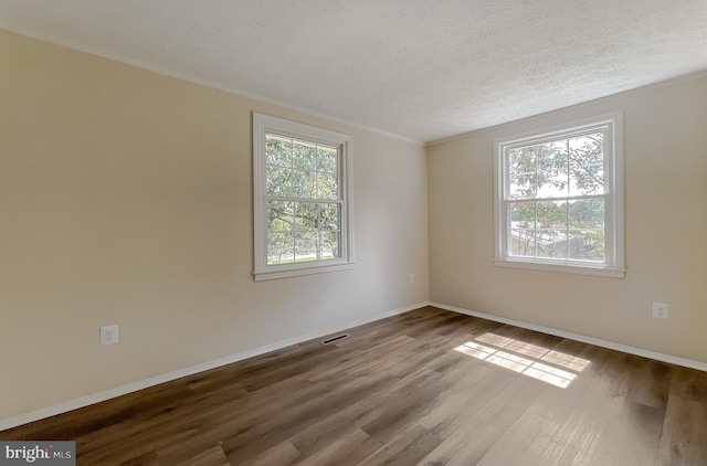 unfurnished room with a textured ceiling, plenty of natural light, ornamental molding, and hardwood / wood-style flooring