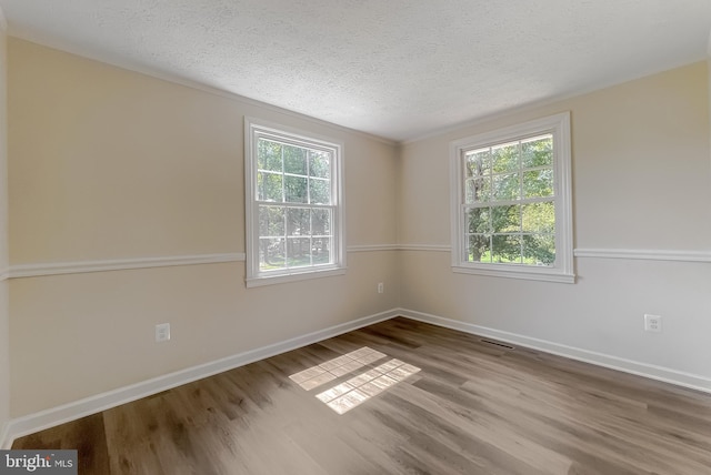 spare room with a textured ceiling and dark hardwood / wood-style flooring