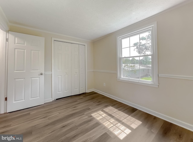 unfurnished bedroom featuring crown molding, a textured ceiling, and wood-type flooring