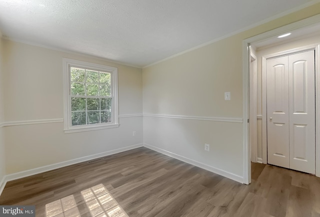 spare room featuring a textured ceiling, ornamental molding, and hardwood / wood-style floors