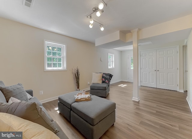 living room with track lighting, decorative columns, and light hardwood / wood-style flooring