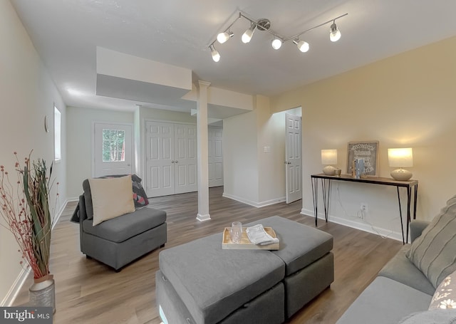 living room featuring track lighting, hardwood / wood-style floors, and ornate columns