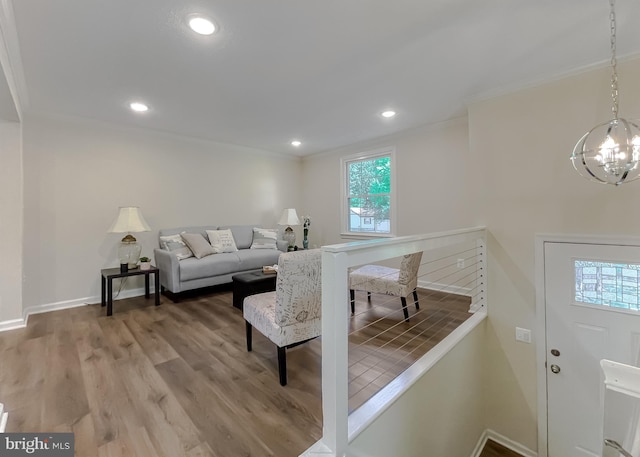 living room featuring hardwood / wood-style floors, an inviting chandelier, and ornamental molding