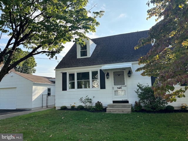 view of front facade with a garage, a front lawn, and an outbuilding