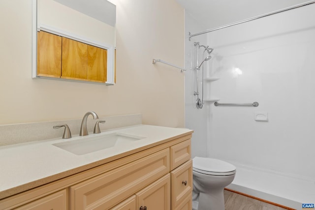 bathroom featuring toilet, a shower, wood finished floors, and vanity