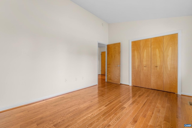 unfurnished bedroom with a closet, visible vents, baseboards, and wood finished floors