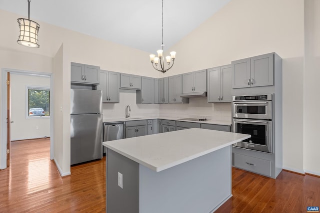 kitchen with appliances with stainless steel finishes, dark wood-type flooring, gray cabinets, light countertops, and high vaulted ceiling