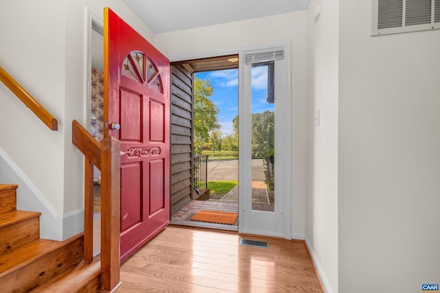 foyer entrance with light wood-type flooring, visible vents, stairway, and baseboards