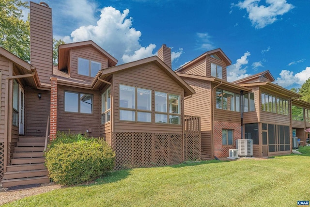 back of property with a sunroom, a chimney, and a yard