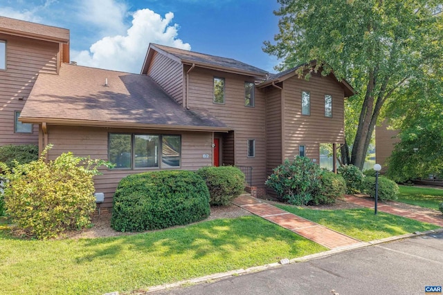 view of front of house featuring a shingled roof and a front yard