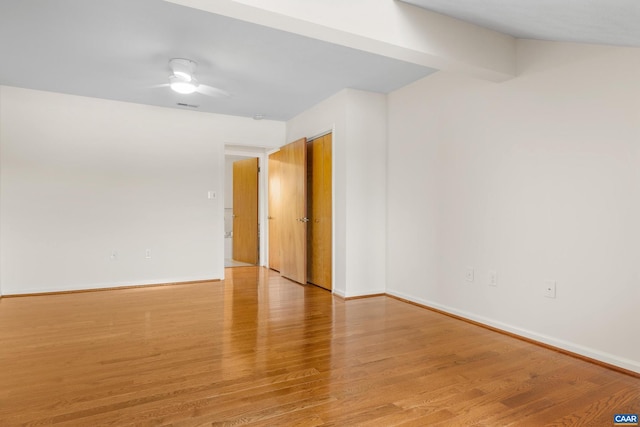 empty room featuring light wood-style floors, visible vents, baseboards, and a ceiling fan