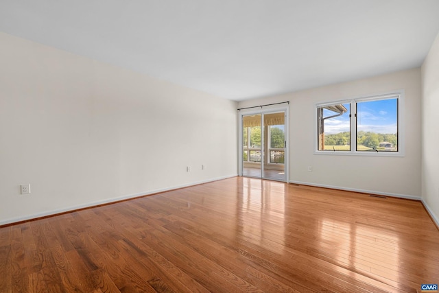 empty room with visible vents, baseboards, and hardwood / wood-style floors