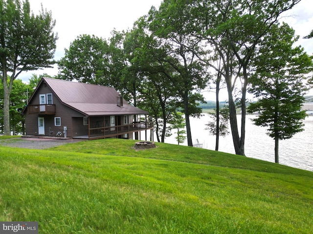 exterior space featuring metal roof, a water view, and a lawn