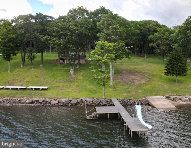 view of dock with a yard and a water view