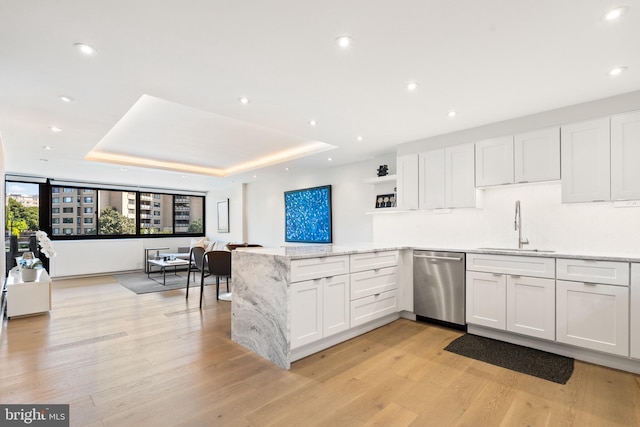kitchen with stainless steel dishwasher, a sink, a peninsula, open shelves, and light wood-style floors