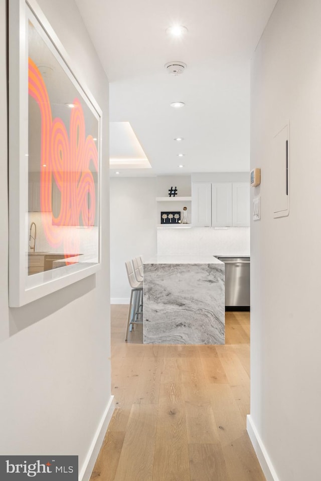 corridor featuring baseboards, recessed lighting, and light wood-type flooring