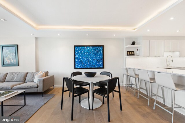 dining space featuring a tray ceiling, recessed lighting, light wood-style floors, and baseboards