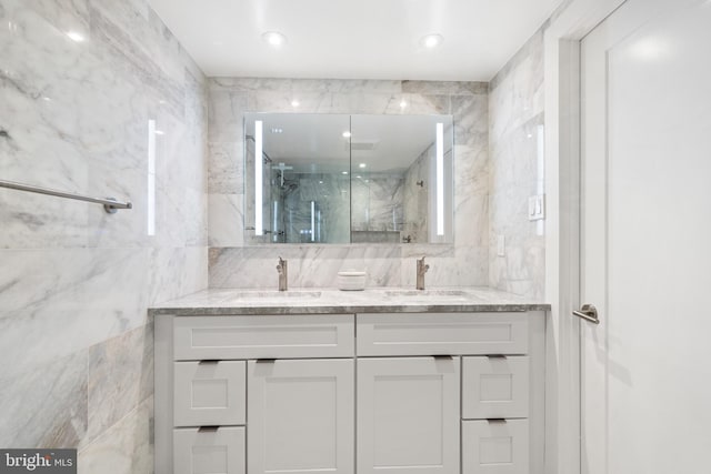 full bathroom featuring tile walls, a marble finish shower, and double vanity