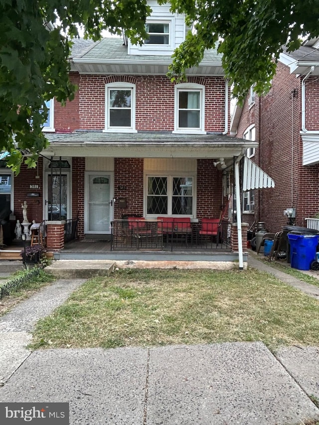 townhome / multi-family property with covered porch and a front yard