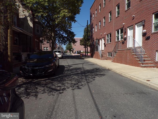 view of street with entry steps, curbs, and sidewalks