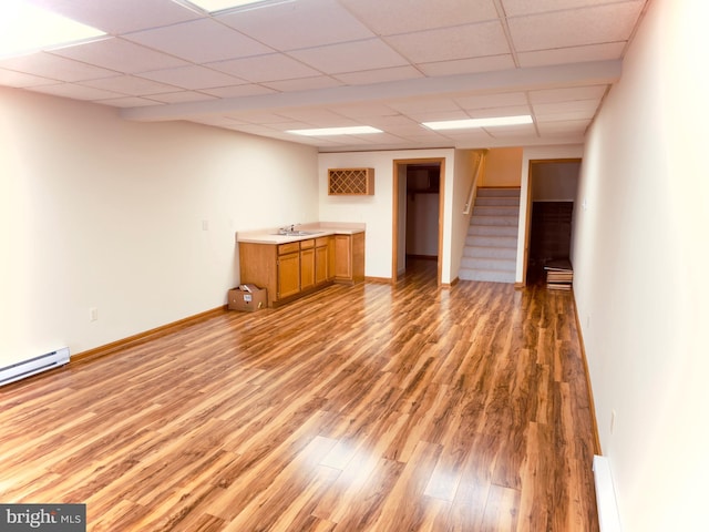 interior space with a paneled ceiling, hardwood / wood-style floors, a baseboard heating unit, and sink