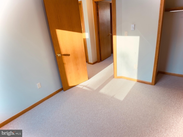 unfurnished bedroom with a closet and light colored carpet