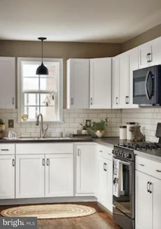 kitchen with gas range, tasteful backsplash, and white cabinetry