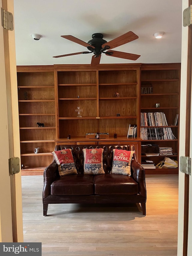 living room with built in shelves, light hardwood / wood-style floors, and ceiling fan