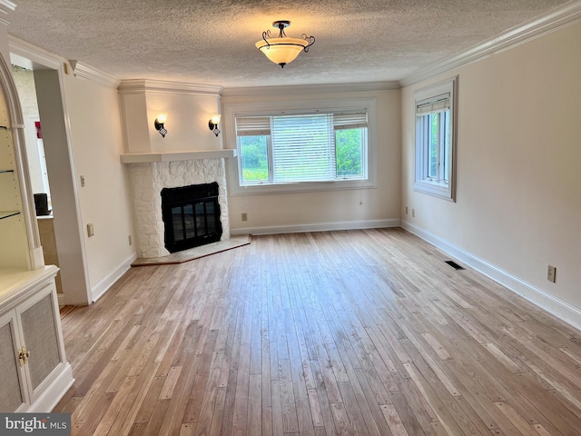 unfurnished living room featuring a textured ceiling, light wood-type flooring, a fireplace, and ornamental molding